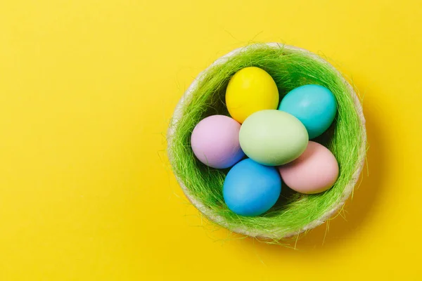 Seis coloridos pastel monofônico pintado ovos de Páscoa em cesta com grama verde isolado no fundo amarelo. Feliz conceito de Páscoa. Espaço de cópia para propaganda. Com lugar para SMS. Vista superior em ovos . — Fotografia de Stock