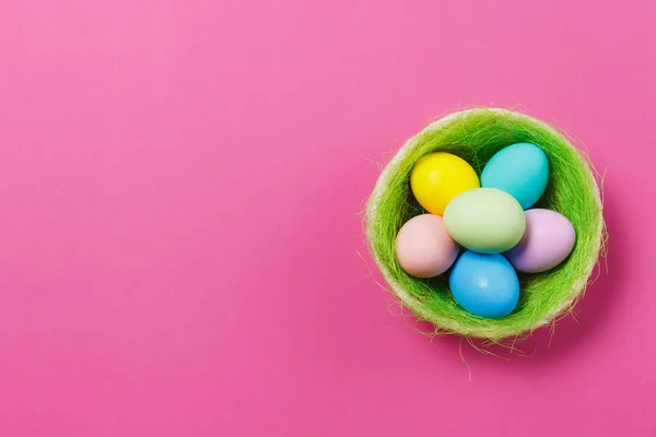 Seis coloridos pastel monofônico pintado ovos de Páscoa em cesta com grama verde isolado no fundo rosa. Feliz conceito de Páscoa. Espaço de cópia para propaganda. Com lugar para SMS. Vista superior em ovos . — Fotografia de Stock