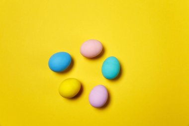 Kartı veya kartpostal Sarı zemin üzerine izole beş renkli pastel tek sesli boyalı Paskalya yumurtaları. Mutlu Paskalya kavramı. Reklam için yer kopyalayın. Metin için yer ile. Yumurta üzerinde Üstten Görünüm.