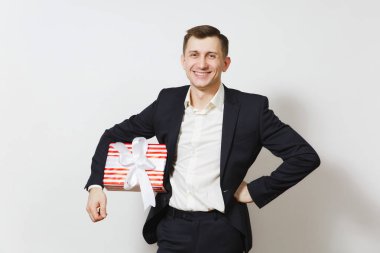 Genç gülümseyen yakışıklı ile hediye izole beyaz zemin üzerine kırmızı mevcut kutu tutan takım elbiseli. Reklam için yer kopyalayın. St. Valentine's Day, Dünya Kadınlar günü doğum günü tatil kavramı