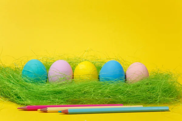 Fila de cinco pastel colorido monofônico pintado ovos de Páscoa, lápis em grama verde no fundo amarelo para cartão ou cartão postal. Feliz conceito de Páscoa. Espaço de cópia para propaganda. Com lugar para texto . — Fotografia de Stock