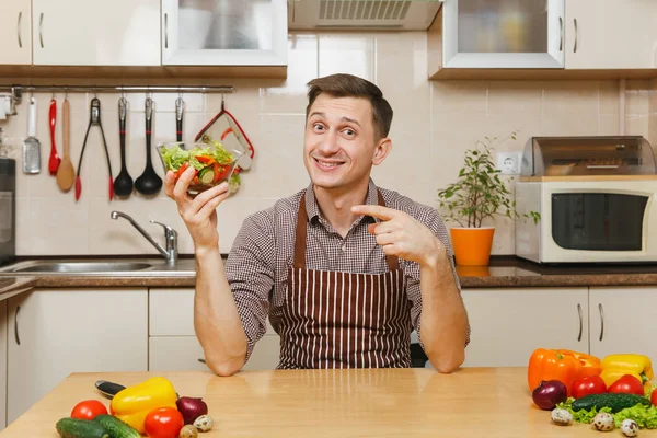 Schöner lächelnder europäischer junger Mann in Schürze, braunes Hemd sitzend — Stockfoto