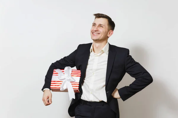 Молодой красивый улыбающийся мужчина в костюме с красной коробкой подарка на белом фоне. Копировать место для рекламы. День святого Валентина, концепция празднования Международного женского дня рождения — стоковое фото