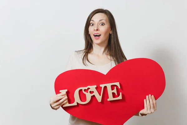 Effektive junge lächelnde Frau mit großem roten Herz, hölzernem Wort Liebe auf weißem Hintergrund. Kopierfläche für Werbung. mit Platz für Text. St. Valentinstag oder Internationaler Frauentag. — Stockfoto