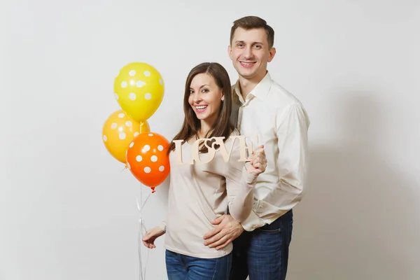 Cute couple in love. Man, woman with wooden word Love, yellow, orange balloons isolated on white background. For advertisement. St. Valentine's Day, International Women's Day, birthday holiday concept — Stock Photo, Image