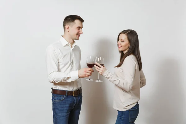 年轻的白种夫妇快乐的微笑的男人和女人在爱的休闲轻便的衣服, 牛仔裤做烤面包, 喝从眼镜的红葡萄酒隔离在白色的背景。广告复制空间. — 图库照片