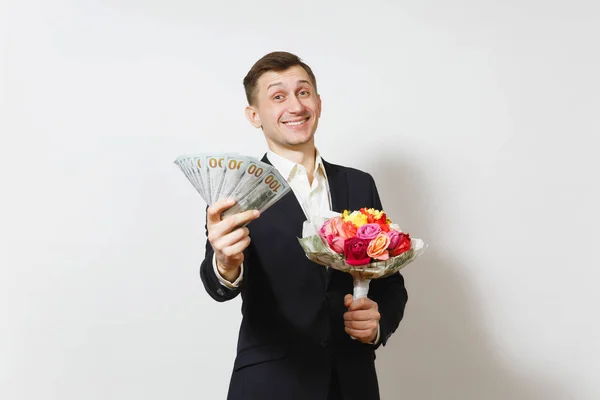 Jeune bel homme en costume avec bouquet de belles fleurs de roses, paquet de dollars d'argent en espèces isolé sur fond blanc. Saint-Valentin, Journée internationale de la femme, concept de fête d'anniversaire . — Photo