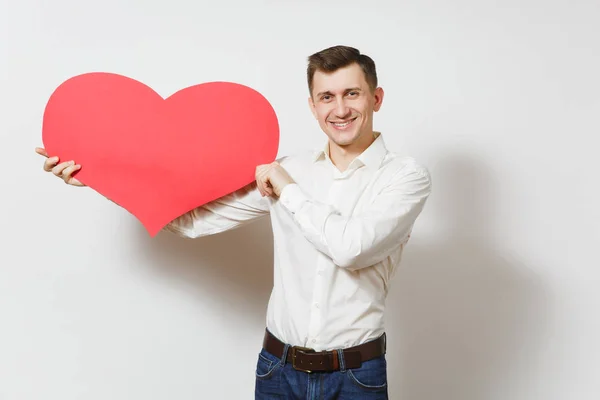 Junger gutaussehender Mann im Hemd, der ein großes rotes Herz auf weißem Hintergrund hält. Kopierraum, Werbung. Platz für Text. st. valentinstag, internationaler frauentag, geburtstag, ferienkonzept. — Stockfoto