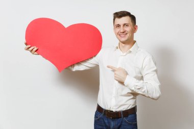 Tişörtlü beyaz arka plan üzerinde izole büyük kırmızı kalp tutan genç yakışıklı adam. Alan, reklam kopyalayın. Metin için yer. St. Valentine's Day, Dünya Kadınlar Günü, doğum günü, konsept tatil.
