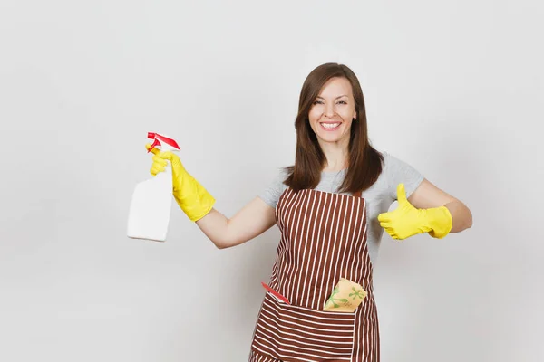 Huisvrouw in gele handschoenen gestreept schort schoonmaken rag zuigmond in zak geïsoleerd op een witte achtergrond. Huishoudster vrouw weergegeven: duim omhoog houden sproeiflacon met schonere vloeistof. Fles kopie ruimte. — Stockfoto