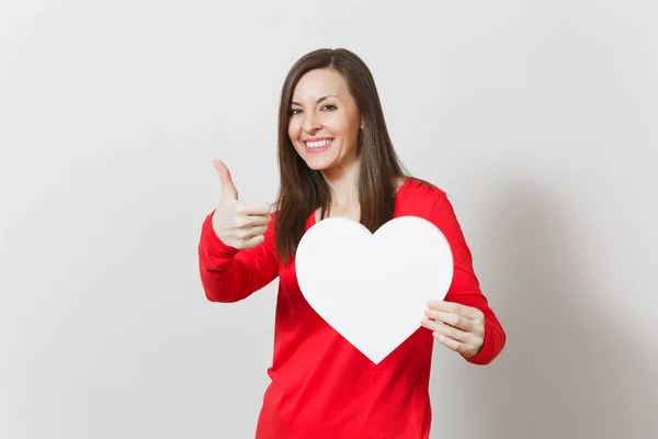 Pretty woman in red clothes showing thumb up, holding big white heart in hands isolated on white background. Copy space for advertisement. St. Valentine's Day or International Women's Day concept. — Stock Photo, Image