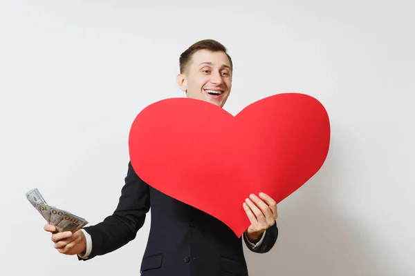 Junger Mann im Anzug mit großem roten Herz, Bündel von Bargeld Dollar isoliert auf weißem Hintergrund. Kopierfläche für Werbung. St. Valentinstag, Internationaler Frauentag, Geburtstagskonzept. — Stockfoto