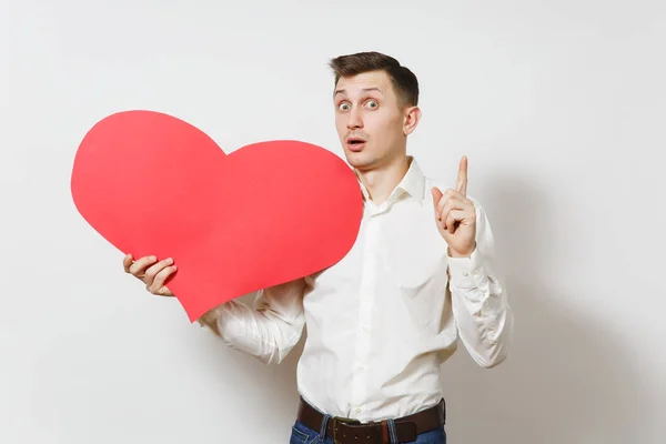 Joven hombre guapo con camisa sosteniendo un gran corazón rojo aislado sobre fondo blanco. Copiar espacio, publicidad. Lugar para el texto. Día de San Valentín, Día Internacional de la Mujer, cumpleaños, concepto de fiesta . — Foto de Stock