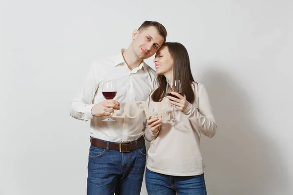 Young caucasian couple. Happy smiling man and woman in love in casual light clothes, jeans making toast, drinking from glasses of red wine isolated on white background. Copy space for advertisement. — Stock Photo, Image