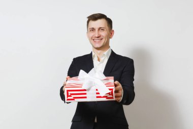 Genç gülümseyen yakışıklı ile hediye izole beyaz zemin üzerine kırmızı mevcut kutu tutan takım elbiseli. Reklam için yer kopyalayın. St. Valentine's Day, Dünya Kadınlar günü doğum günü tatil kavramı