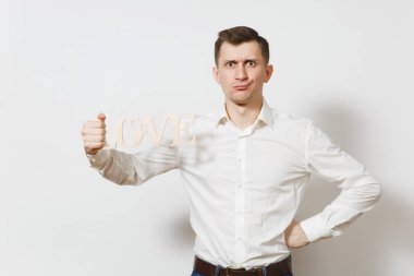 Genç Word'de aşk izole gömlek holding ahşap beyaz zemin üzerine kızgın adam eğlenceli. Reklam için yer kopyalayın. St. Valentine's Day, Dünya Kadınlar Günü, doğum günü, konsept tatil.