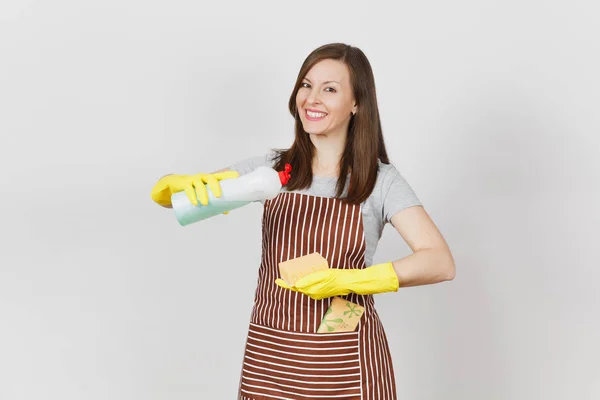 Ung hemmafru i gula handskar, randiga förkläde, rengöring rag i ficka isolerade på vit bakgrund. Kvinna häller renare vätska för att diska ur flaska på svamp. Kopiera utrymme för reklam. — Stockfoto