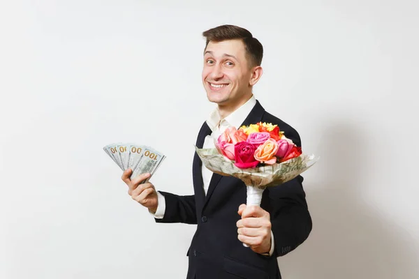 Молодой красивый мужчина в костюме с букетом красивых цветов роз, связкой денежных долларов, выделенных на белом фоне. День святого Валентина, Международный женский день, концепция праздника дня рождения . — стоковое фото