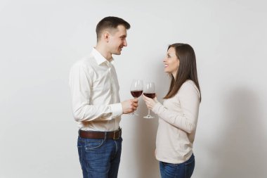 Genç çift. Mutlu erkek ve kadın rahat hafif kıyafetler aşık gülümseyen, kırmızı bardak içmek tost ekmegi kot üzerinde izole beyaz arka plan şarap. Kopya alanı reklam için.