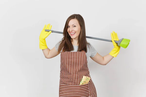 Joven ama de casa sonriente en delantal rayado, guantes amarillos aislados sobre fondo blanco. Mujer ama de llaves limpiando criada sosteniendo y barriendo con escoba. Copia espacio para la publicidad. Área publicitaria . —  Fotos de Stock