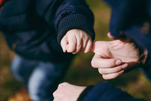 Närbild av kvinna promenader med lilla barn baby boy i varm höst park. Liten unge son håller pekfingret av hans mor med handen. Föräldraskap, familj dag 15 maj, kärlek, föräldrar, barn koncept. — Stockfoto