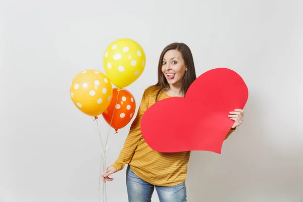 Mujer joven sosteniendo un gran corazón rojo, globos amarillos anaranjados aislados sobre fondo blanco. Copia espacio para la publicidad. Con lugar para el texto. San Valentín o concepto del Día Internacional de la Mujer . — Foto de Stock