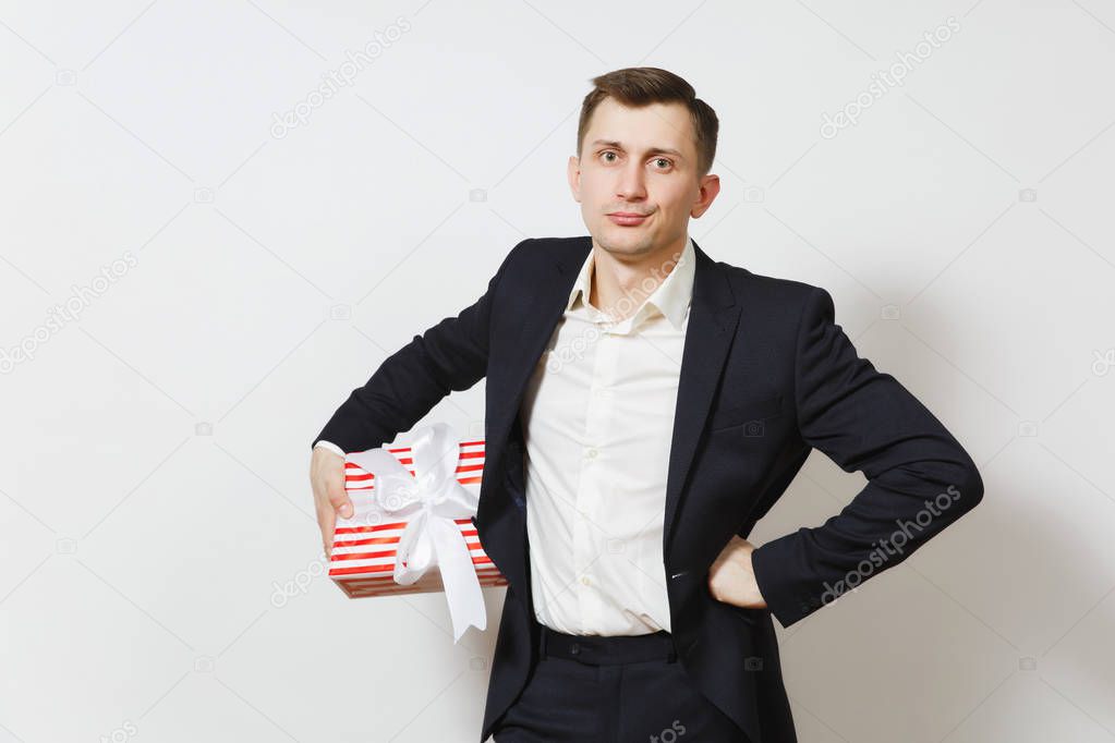 Young stunned upset man in suit holding red present box with gift isolated on white background. Copy space for advertisement. St. Valentine's Day, International Women's Day birthday holiday concept.