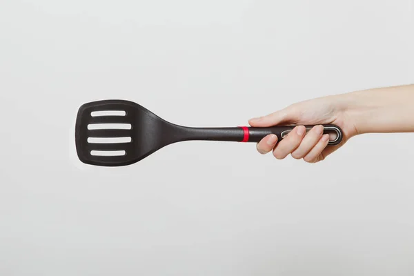 Close up of female hand horizontal holding black spatula isolated on white background. Kitchen utensils concept. Copy space for advertisement. — Stock Photo, Image