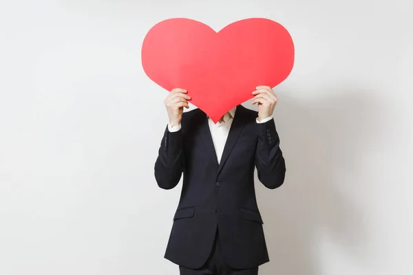 Hombre joven en traje cubriendo la cara con un gran corazón rojo aislado sobre fondo blanco. Copia espacio para la publicidad. Lugar para el texto. Día de San Valentín, Día Internacional de la Mujer, cumpleaños, concepto de fiesta . — Foto de Stock