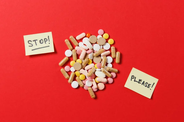 Лекарства белые красочные круглые таблетки расположены абстрактно на красном фоне цвета. Аспирин, капсульные таблетки, лист бумаги, текст стоп, пожалуйста. Обращение, лечение, выбор концепции здорового образа жизни . — стоковое фото