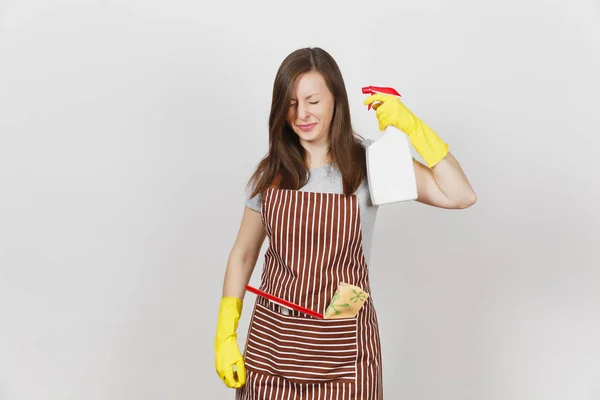 Jonge leuke huisvrouw in gele handschoenen, gestreepte schort, reiniging rag, zuigmond in zak geïsoleerd op een witte achtergrond. Huishoudster vrouw scheuten van sproeiflacon met schonere vloeistof. Fles kopie ruimte. — Stockfoto
