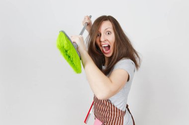 Genç tousled deli baş döndürücü kaçık vahşi agresif ev kadını saç çizgili önlük pembe eldiven beyaz arka plan üzerinde izole cebinde eğlenceli. Cadı kadın saldırı süpürge ile. Kopya alanı reklam için.