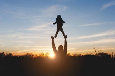 Adam yüksek silüeti at doğa, sunset horizon arka plan üzerinde küçük şirin çocuk oğlu kadar. Babası atmak eğlenceli küçük oğlu açık havada evlat. Aile günü 15 Mayıs, sevgi, anne, çocuk kavramı.
