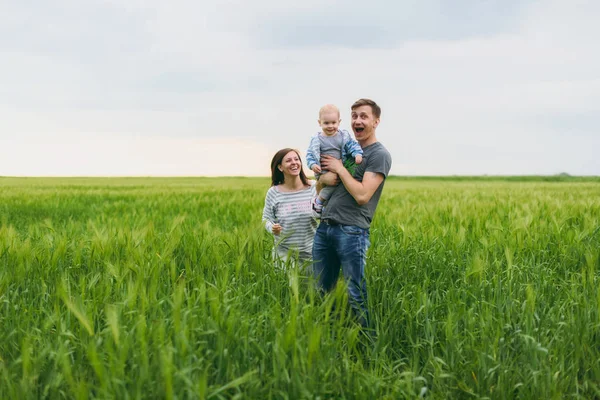 Fröhlicher Mann, Frau gehen auf der grünen Wiese Hintergrund, Ruhe, Spaß haben, spielen, stehen mit kleinen niedlichen Kind Baby Boy. Mutter, Vater, kleiner Sohn. Familientag 15. Mai, Liebe, Eltern, Kinder. — Stockfoto