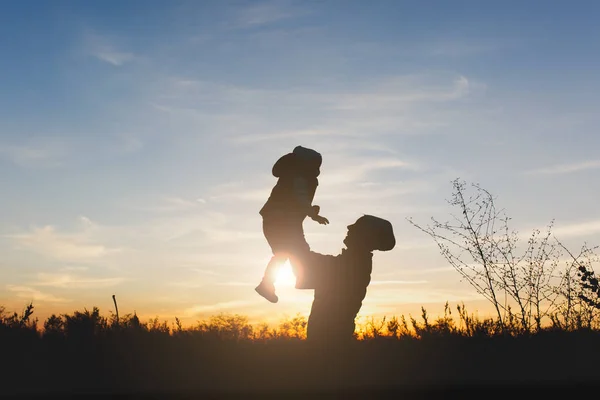 Yüksek kadın silüeti at doğa, sunset horizon arka plan üzerinde küçük şirin çocuk oğlu kadar. Anne atmak eğlenceli küçük oğlu açık havada evlat. Aile günü 15 Mayıs, sevgi, anne, çocuk kavramı. — Stok fotoğraf