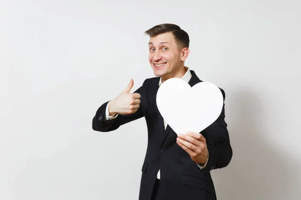 Junger Mann im Anzug mit erhobenem Daumen, großes weißes Herz auf weißem Hintergrund. Kopierraum, Werbung. Platz für Text. st. valentinstag, internationaler frauentag, geburtstag, ferienkonzept. — Stockfoto