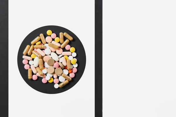 Medicinering vit färgglada runda tabletter ordnade abstrakt i cirkel på vit svart bakgrund. Acetylsalicylsyra, kapsel piller design. Behandling, val hälsosam livsstilskoncept. Kopiera utrymme för reklam. — Stockfoto