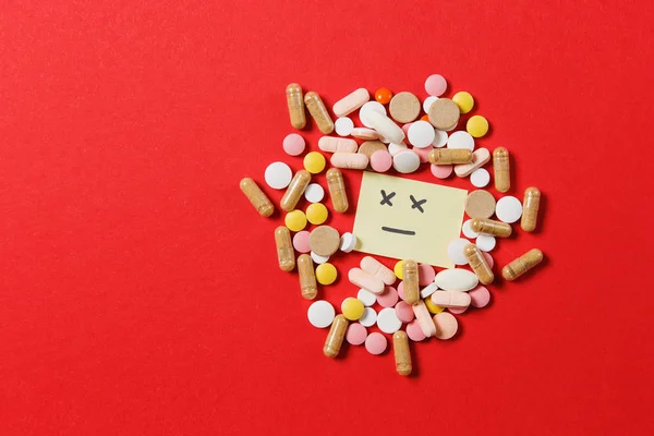 Het kleurrijke ronde tabletten medicatie witte geregeld abstract op rode kleur achtergrond. Aspirine, capsule pillen, papieren sticker vellen, triest glimlach gezicht. Beroep, behandeling, keuze gezonde levensstijl concept. — Stockfoto
