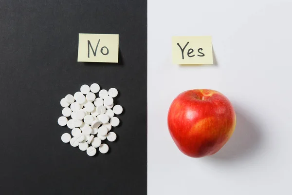 Лекарства белые красочные круглые таблетки расположены абстрактно на белом черном фоне. Красное яблоко, наклейка с текстом да нет, аспирин, таблетки дизайн. Выбор лечения концепции здорового образа жизни. Копирование пространства . — стоковое фото