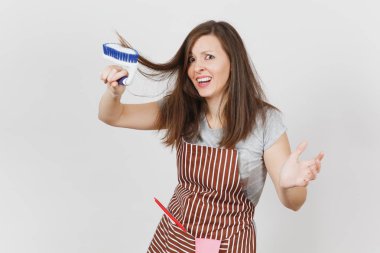 Genç deli baş döndürücü kaçık vahşi ev kadını çizgili önlük beyaz arka plan üzerinde izole cebinde camsil, pembe eldiven ile eğlenceli. Deli kadın dışarı tarak fırça Temizleme tarafından Kahverengi saç tousled. Kopya alanı.