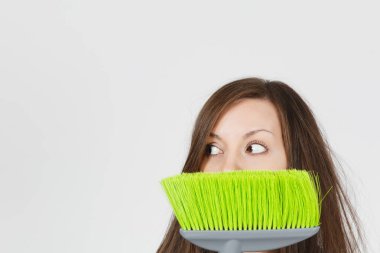 Genç eğlenceli deli baş döndürücü kaçık vahşi korkmuş ev hanımı ile beyaz arka plan üzerinde izole saç tousled kapatın. Deli hizmetçi kadın yeşil süpürge saklanıyor. Kopya alanı reklam için.