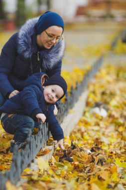 Sarı renk ile yürüyen kadın park küçük şirin çocuk oğlu ile doğa düşmek. Anne, küçük çocuk evlat kontur okşa üç renkli sokak kedileri. Ebeveynlik, Aile günü 15 Mayıs, sevgi, anne, çocuk kavramı