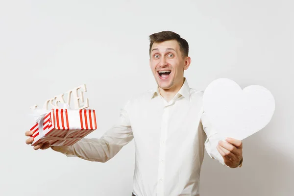 Mladí zábavné usmívající se muž drží velké bílé srdce, dřevěné slovo láska, krabičce s darem izolovaných na bílém pozadí. Den svatého Valentýna, Mezinárodní den žen, narozeniny, svátek koncept. — Stock fotografie