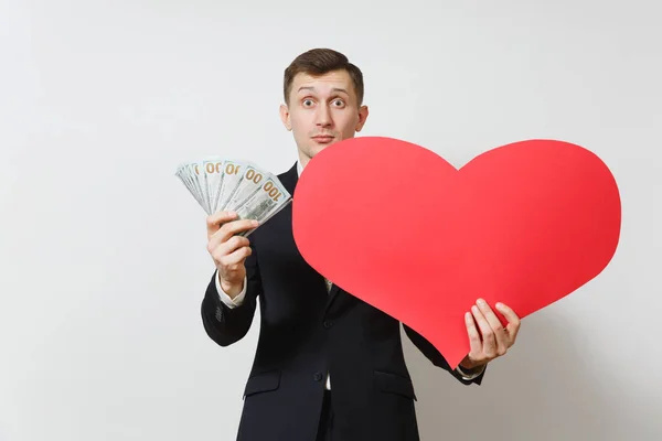 Homem jovem de terno com grande coração vermelho, pacote de dinheiro em dinheiro dólares isolados em fundo branco. Espaço de cópia para propaganda. Dia de São Valentim, Dia Internacional da Mulher, conceito de feriado de aniversário . — Fotografia de Stock