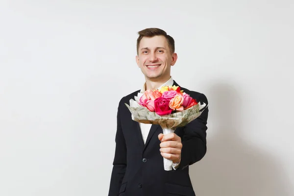 Joven guapo sonriente encantador hombre de traje, camisa sosteniendo ramo de hermosas rosas flores aisladas sobre fondo blanco. Día de San Valentín, Día Internacional de la Mujer, cumpleaños, concepto de fiesta . — Foto de Stock