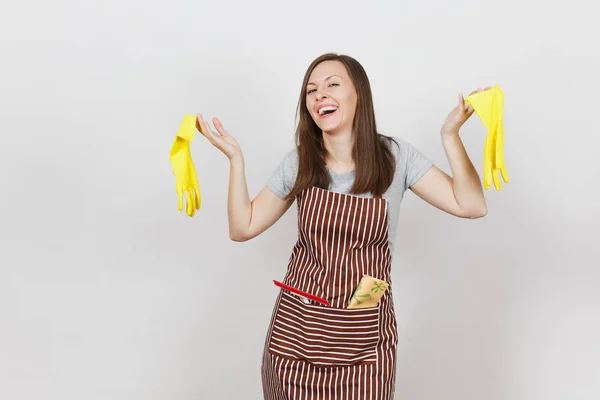 Jeune femme au foyer souriante en tablier rayé avec chiffon nettoyant dans une poche isolée sur fond blanc. Jolie femme de ménage tenant des gants jaunes en écartant les mains, regardant caméra. Pour la publicité — Photo