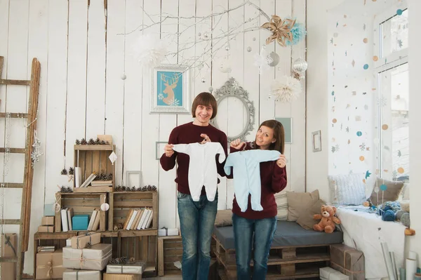 Mujer joven embarazada feliz con barriga grande, hombre en la sala de decoración. Pareja con ropa de niño. Esposa, marido. Embarazo, paternidad, familia, maternidad, padres, hijos, personas y concepto de expectativa — Foto de Stock