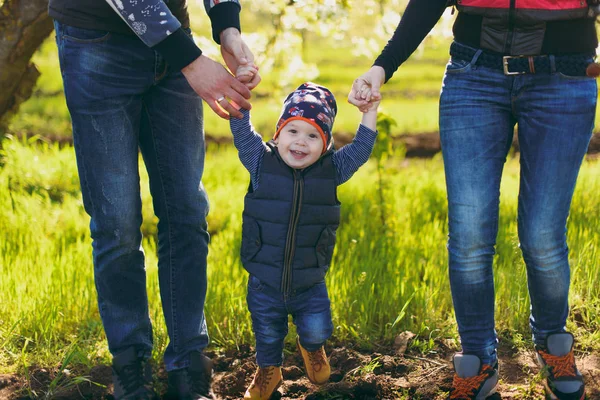 Homem, mulher de jeans descansa no abraço da natureza, brincar, beijar com pequeno menino bonito. Mãe, o pai dá as mãos ao rapazinho na relva verde. Dia de família 15 de maio, amor, pais, conceito de crianças . — Fotografia de Stock