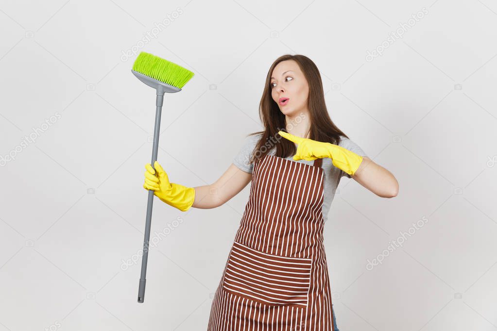 Young smiling housewife in striped apron, yellow gloves isolated on white background. Fun housekeeper woman cleaning maid holding and sweeping with broom. Copy space for advertisement Advertising area