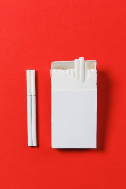 Paket sigara kırmızı zemin üzerine beyaz. Sağlık, seçim, sağlıklı yaşam konsepti. Reklam için yer kopyalayın. Metin için yer ile. Duman durdurmak.